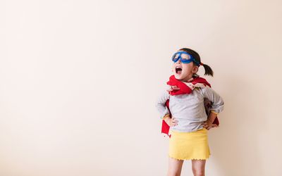 Little girl dressed as superhero standing with hands on her hips