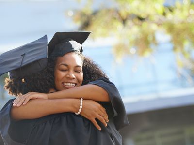woman in graduation gown hugging someone
