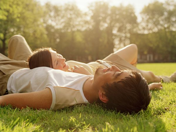 man and woman lying on the grass, woman is lying on man's stomach