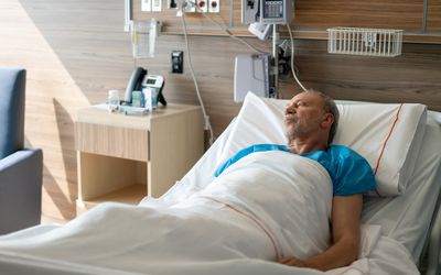Man in hospital bed being treated for complications of end-stage alcoholism