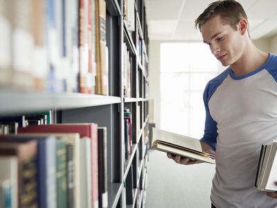 Male student choosing books in college library