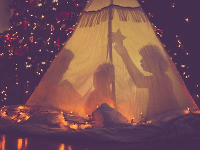 children playing in a tent in front of a Christmas tree