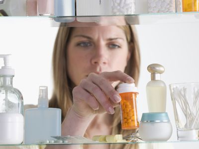 Woman Taking Pill Bottle Out of Cabinet