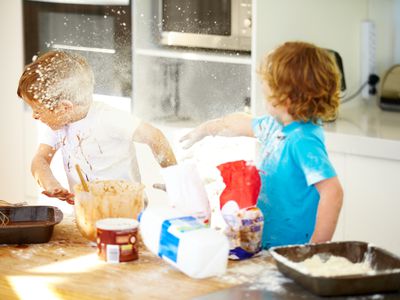 little boys throwing flour at each other in the kitchen