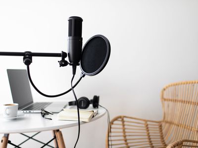 Audio studio with laptop, microphone with pop filter and headphones on white table