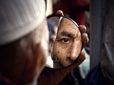 Older man looks into a small mirror