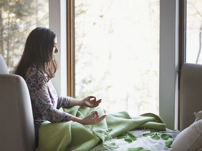 woman meditating at home on bed