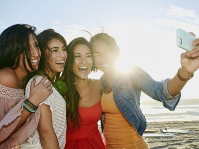 Women taking pictures together on beach